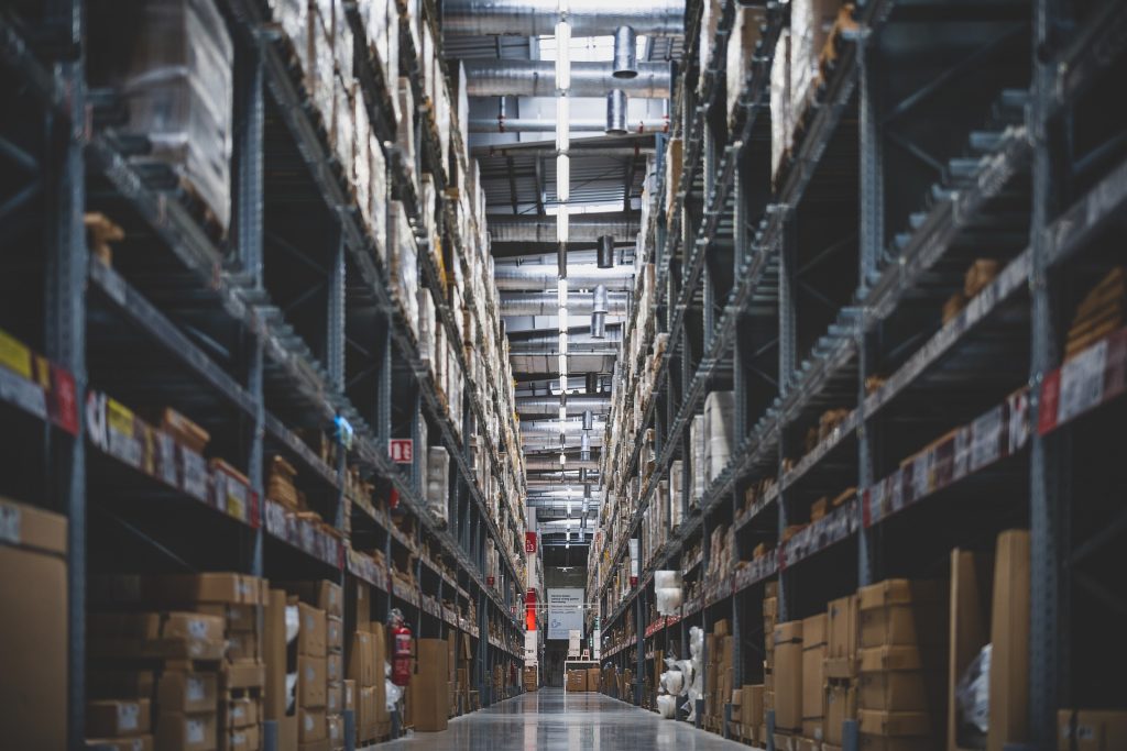 mörk lagergång pallställ högt i tak industribelysning